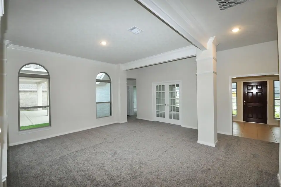 Living area with arched windows and kitchen opening at 3821 Verde River Road, League City, Texas