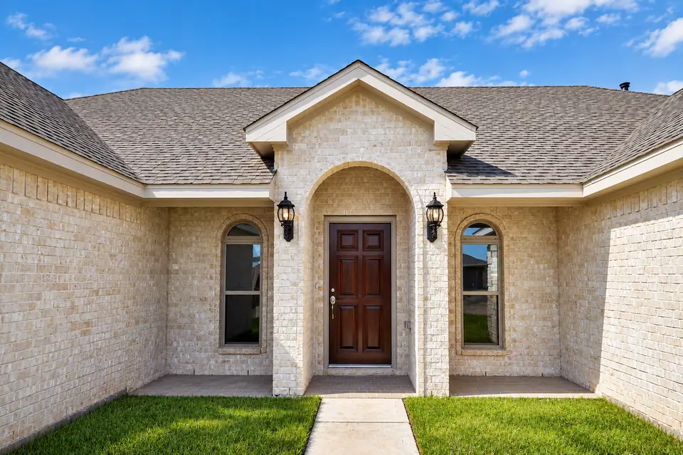 Brick entrance with an arched porch and wood front door