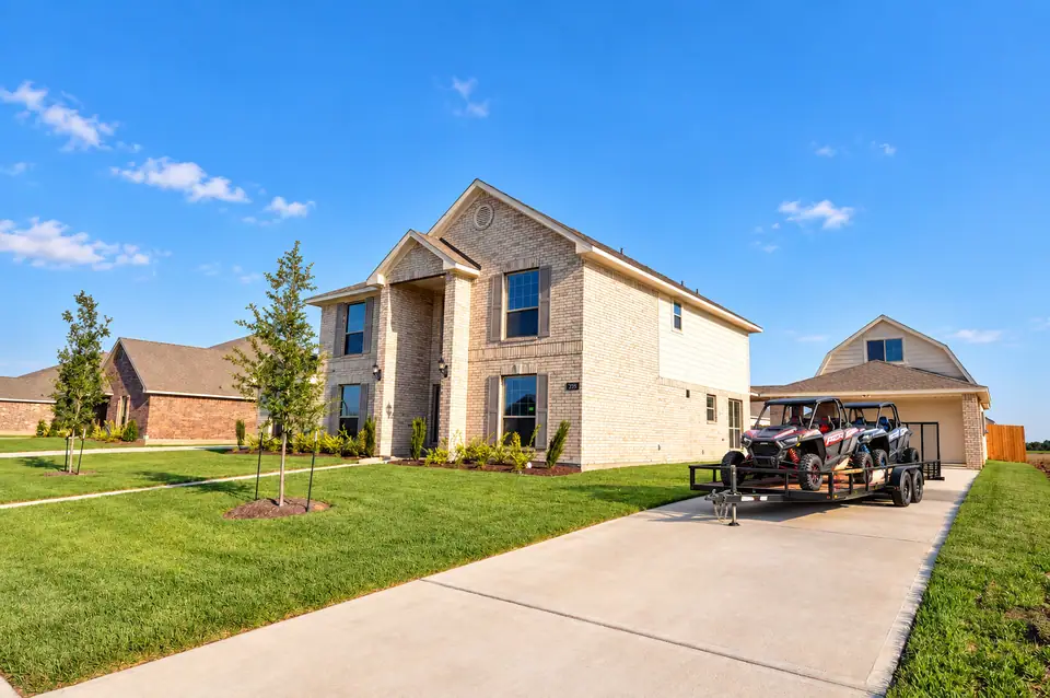 Two-story brick home with off-road vehicles in the driveway