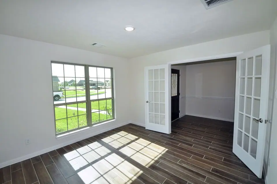 Room with glass doors, front window and wood-look flooring at 3805 Verde River Road, League City, Texas