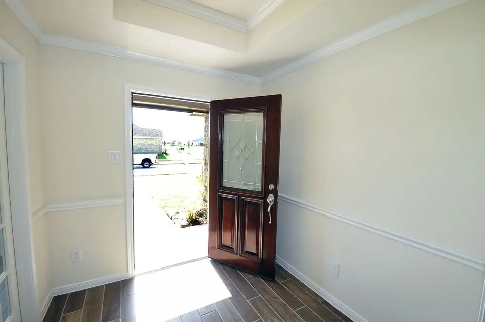 Entry foyer with a tray ceiling and open wood door at 3805 Verde River Road, League City, Texas