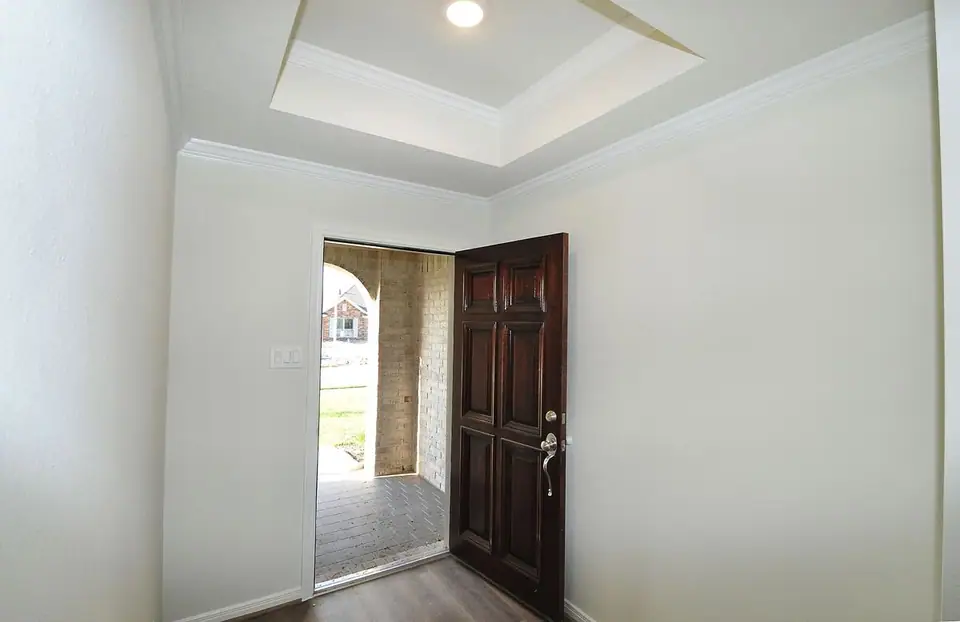 Entry foyer with a tray ceiling and wood front door at 2231 Ensenada Drive, League City, Texas